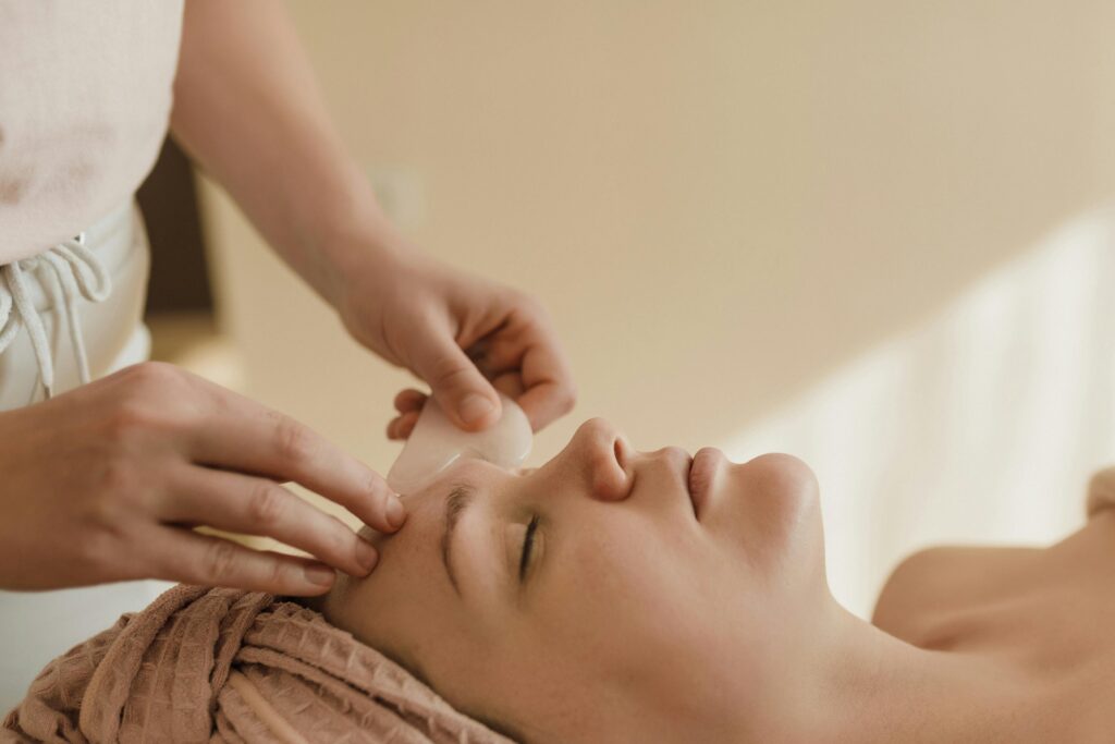 Home page A calming side view of a woman receiving a gua sha facial massage indoors, promoting healthy skin.