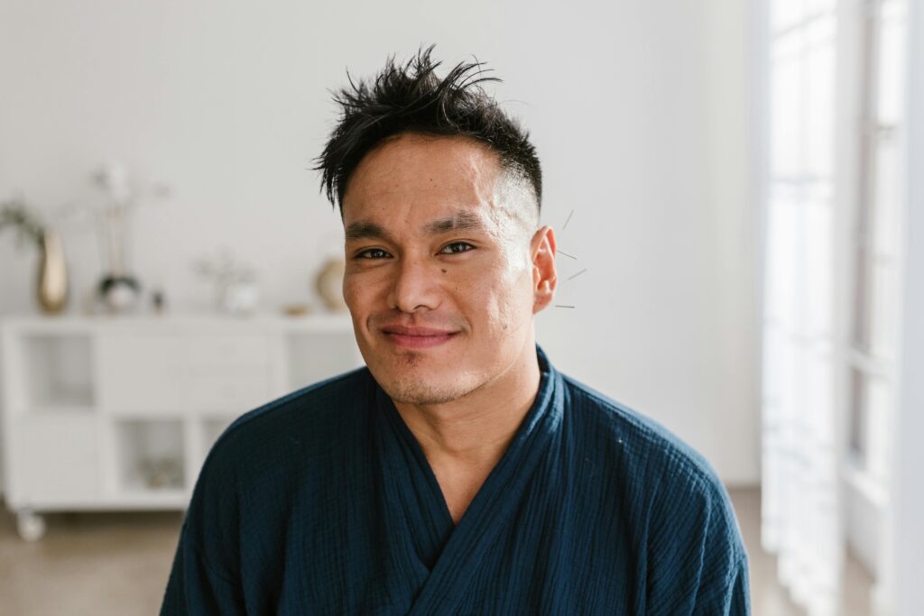 Home page Portrait of a smiling man receiving acupuncture treatment indoors, promoting wellness and alternative medicine.